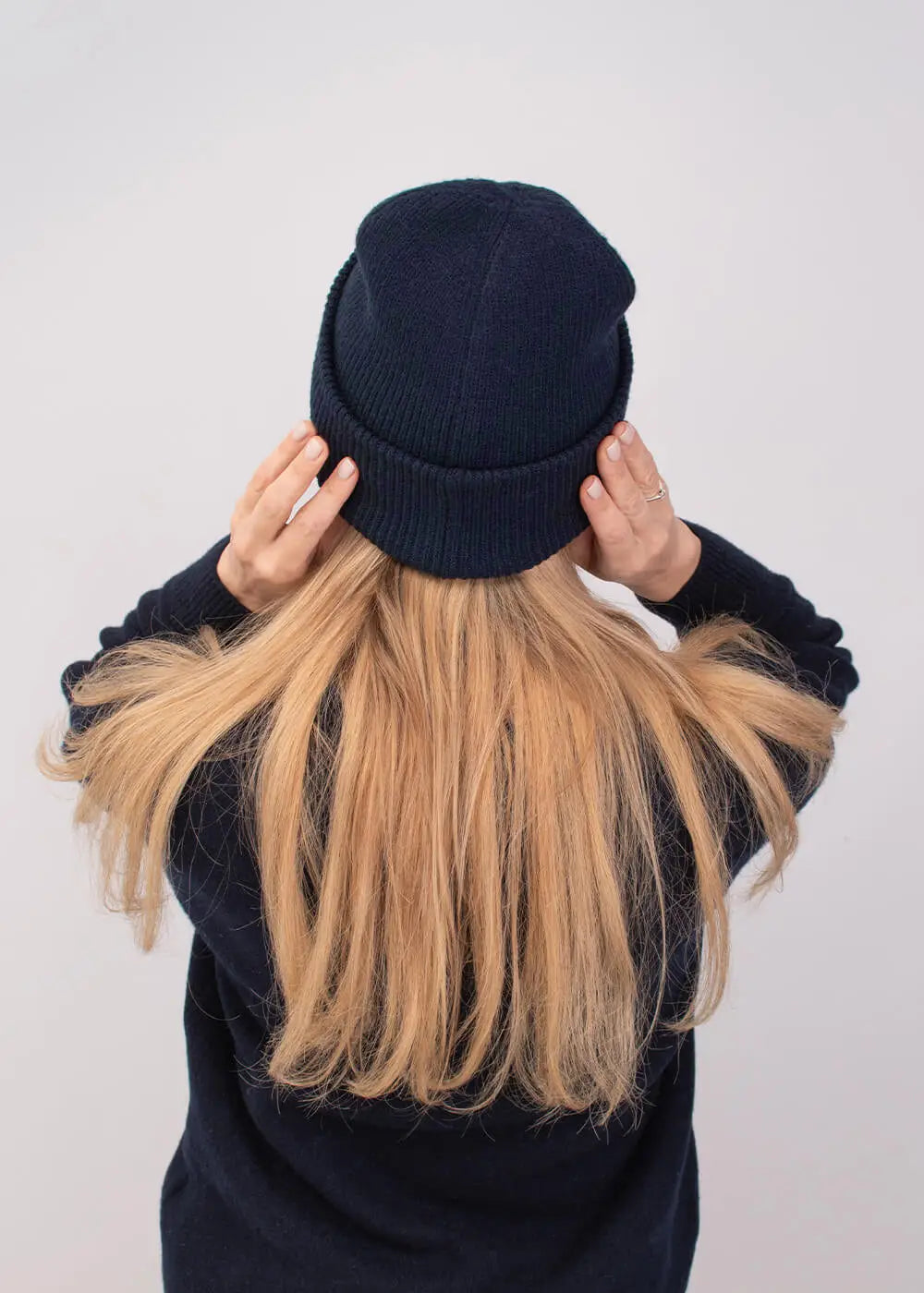 Person mit langen blonden Haaren in einer J.Clay Deep Cuffed Beanie French Navy, von hinten gesehen.