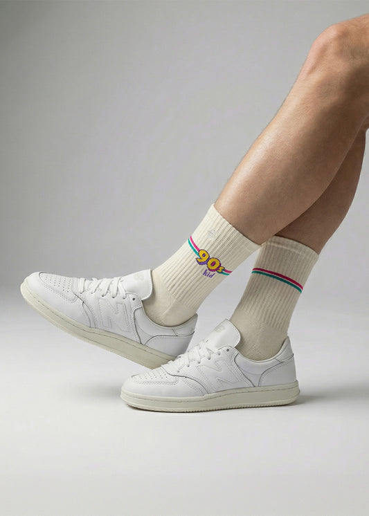 Person in weißen Turnschuhen und J.Clay 90s Kid-Socken mit Regenbogenstreifen und P.O.P.-Aufschrift.