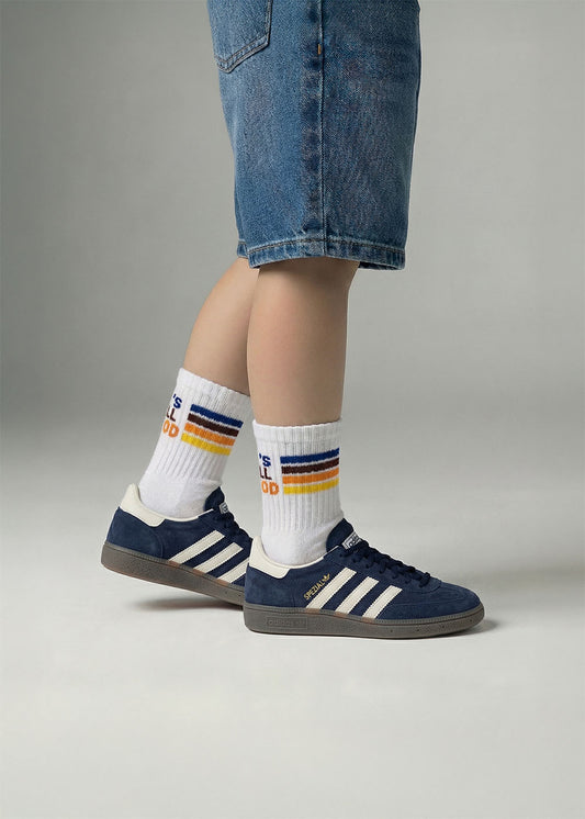 Person in Jeans-Shorts trägt J.Clay All Good - Kids Socken mit navy Adidas Turnschuhen auf grauem Hintergrund.