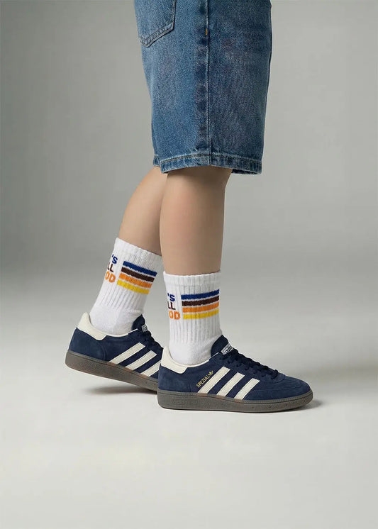 Person in Jeans-Shorts trägt J.Clay All Good - Kids Socken mit navy Adidas Turnschuhen auf grauem Hintergrund.