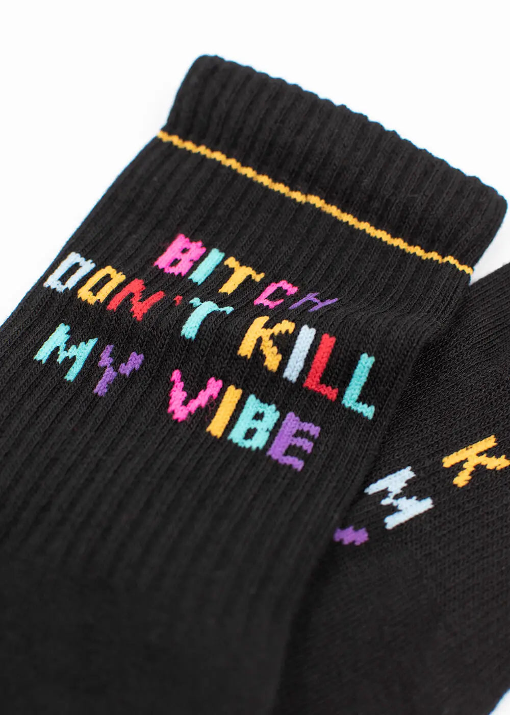 Ein Paar schwarze J.Clay Tennissocken mit einem gelben Bündchenstreifen, auf dem in Blockbuchstaben der bunte Satz "Bitch Dont Kill My Vibe" gestickt ist.