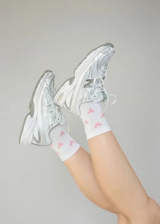 Beine hochgelegt, trägt J.Clay Bowtiful - Midi weiße Socken mit rosa Muster und weiße Turnschuhe.