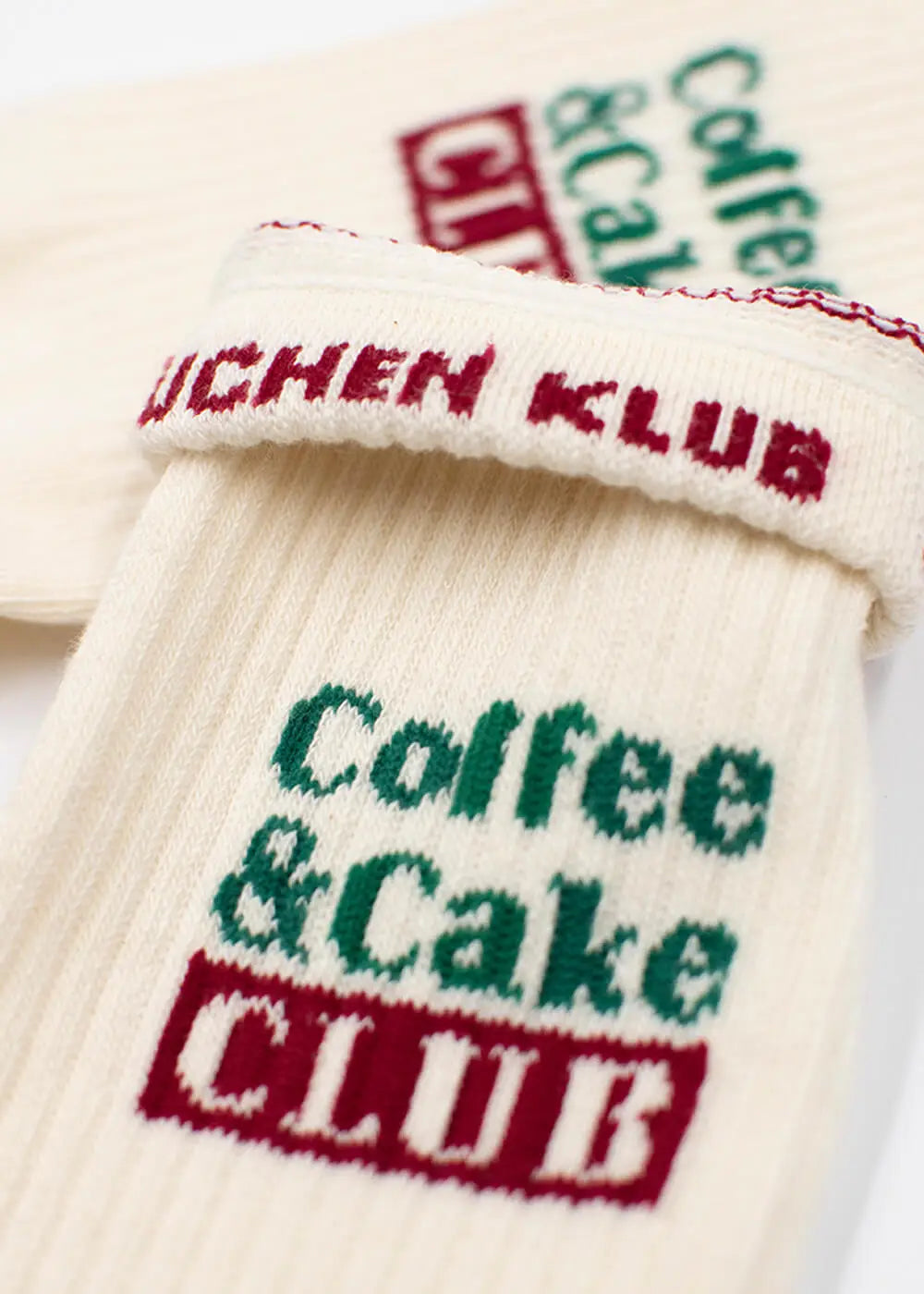 Cremefarbene J.Clay-Socken mit gesticktem Coffee Cake Club-Text in Grün und Rot.