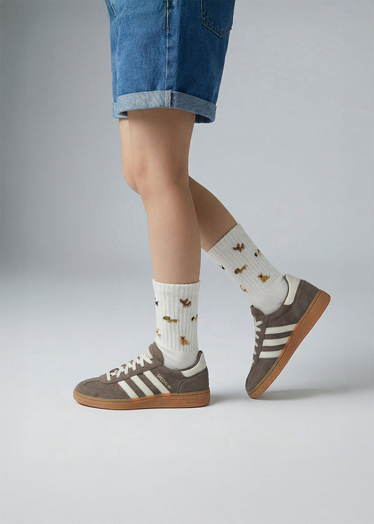 Person in Jeansshorts, braunen Adidas-Turnschuhen und J.Clay Doggie - Kids im Schneidersitz.