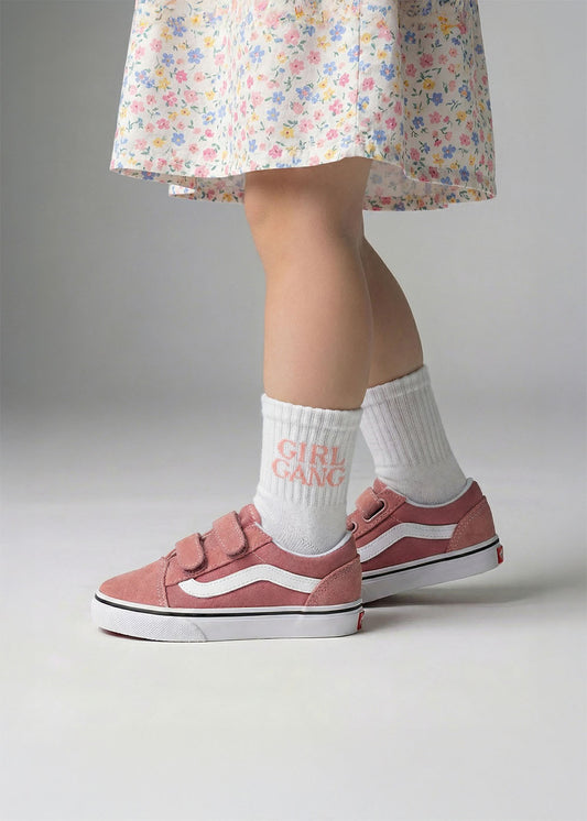 Sie trägt ein geblümtes Kleid, rosa Turnschuhe und J.Clay Girl Gang - Mini Socken.