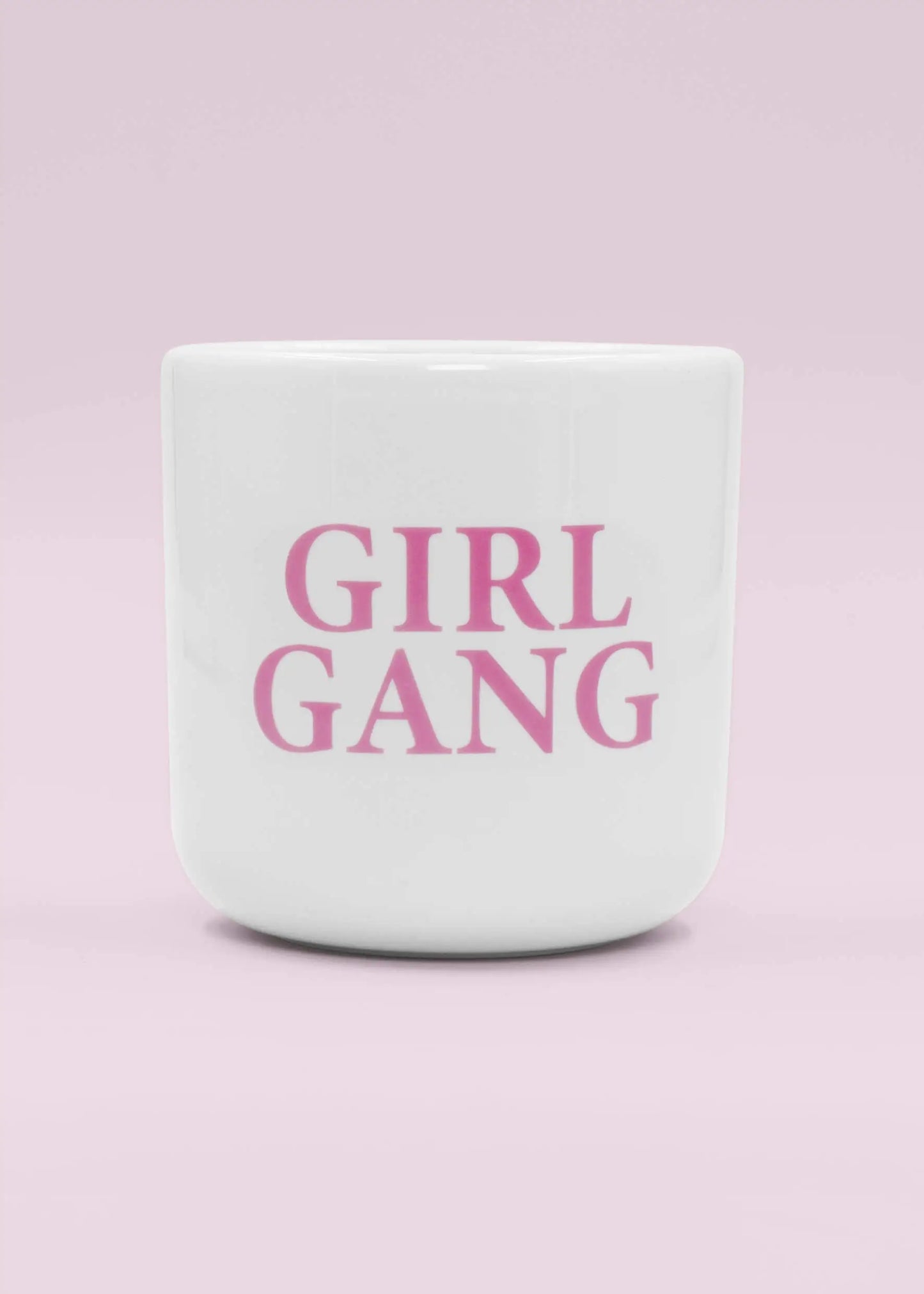 Der weiße Keramikbecher ohne Henkel von J.Clay zeigt GIRL GANG in fetten rosa Buchstaben auf einem hellrosa Hintergrund - perfekt, um Momente mit deinem Girl Gang Pack zu teilen.