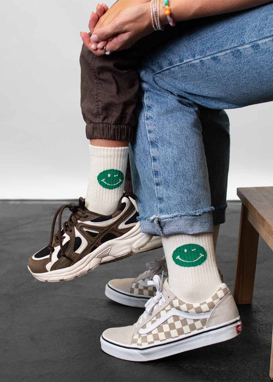 Zwei tragen Socken von J.Clay Green Smile – Fam Pack, kombiniert mit modischen Sneakern.