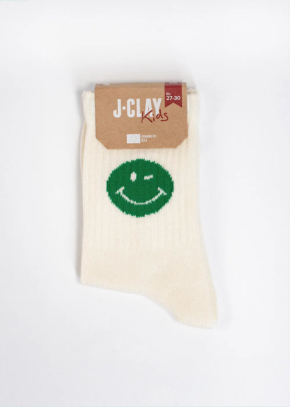 Ein Paar cremefarbene J.Clay Kindersocken mit einem großen grünen Lächel-Motiv auf dem Knöchel, vor weißem Hintergrund und mit einem braunen Pappetikett mit der Aufschrift "J-CLAY Kids" versehen.