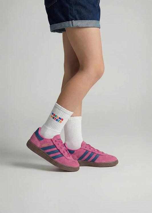 Person in rosa Turnschuhen, Jeansshorts und J.Clay Hakuna Matata - Kids Socken in Weiß.