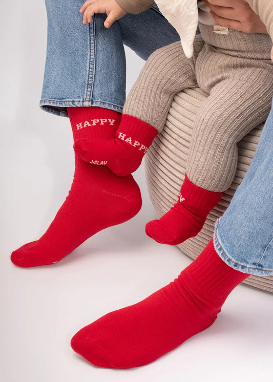 Erwachsener und Kind in J.Clay Happy - Kids Socken, zusammen auf einem gepolsterten Sitz sitzend.
