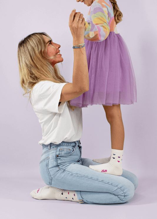 Zwei Paar J.Clay Partner-Look Socken, ein kleines und ein großes, in Creme mit rosa und lila Herzmustern. Beide Paare sind auf weißem Hintergrund abgebildet. - Mama Kind Packs