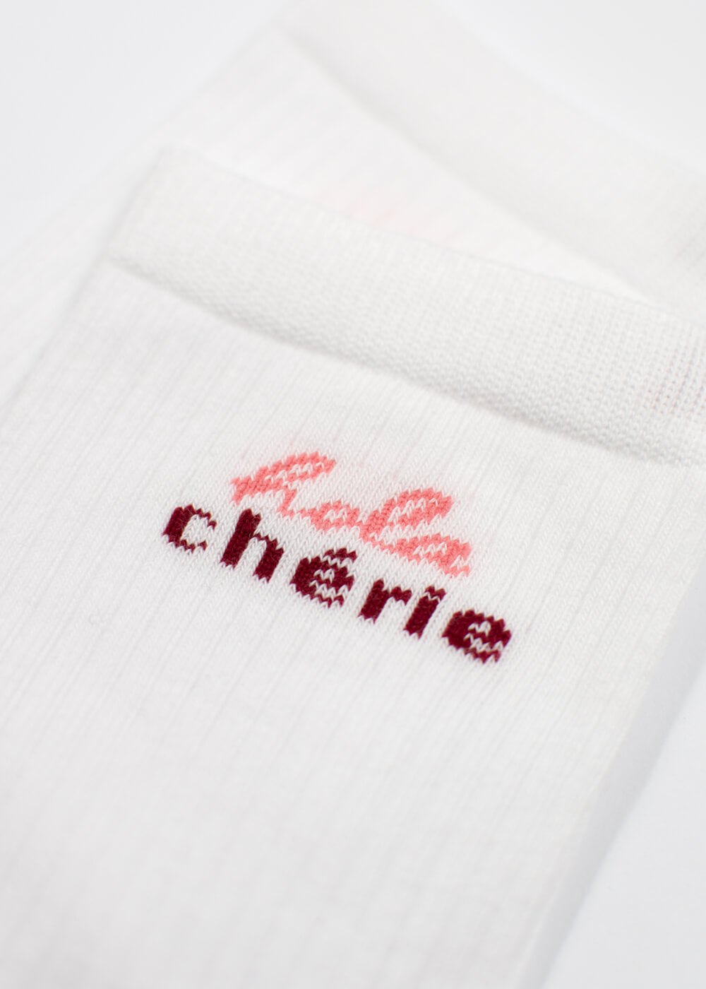 Weiße gerippte J.Clay Hola Chérie - Midi-Socken mit rosa und burgunderrotem Bébé Chérie-Text am Bündchen.
