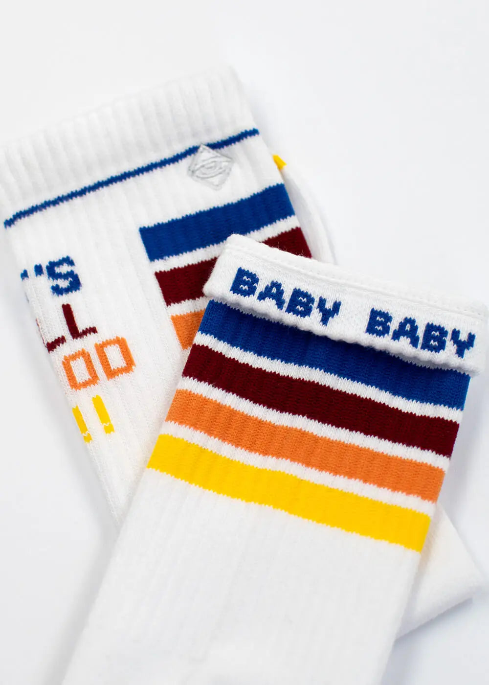 J.Clay All Good weiße Socken mit bunten Streifen und "BABY BABY" auf dem Bündchen.