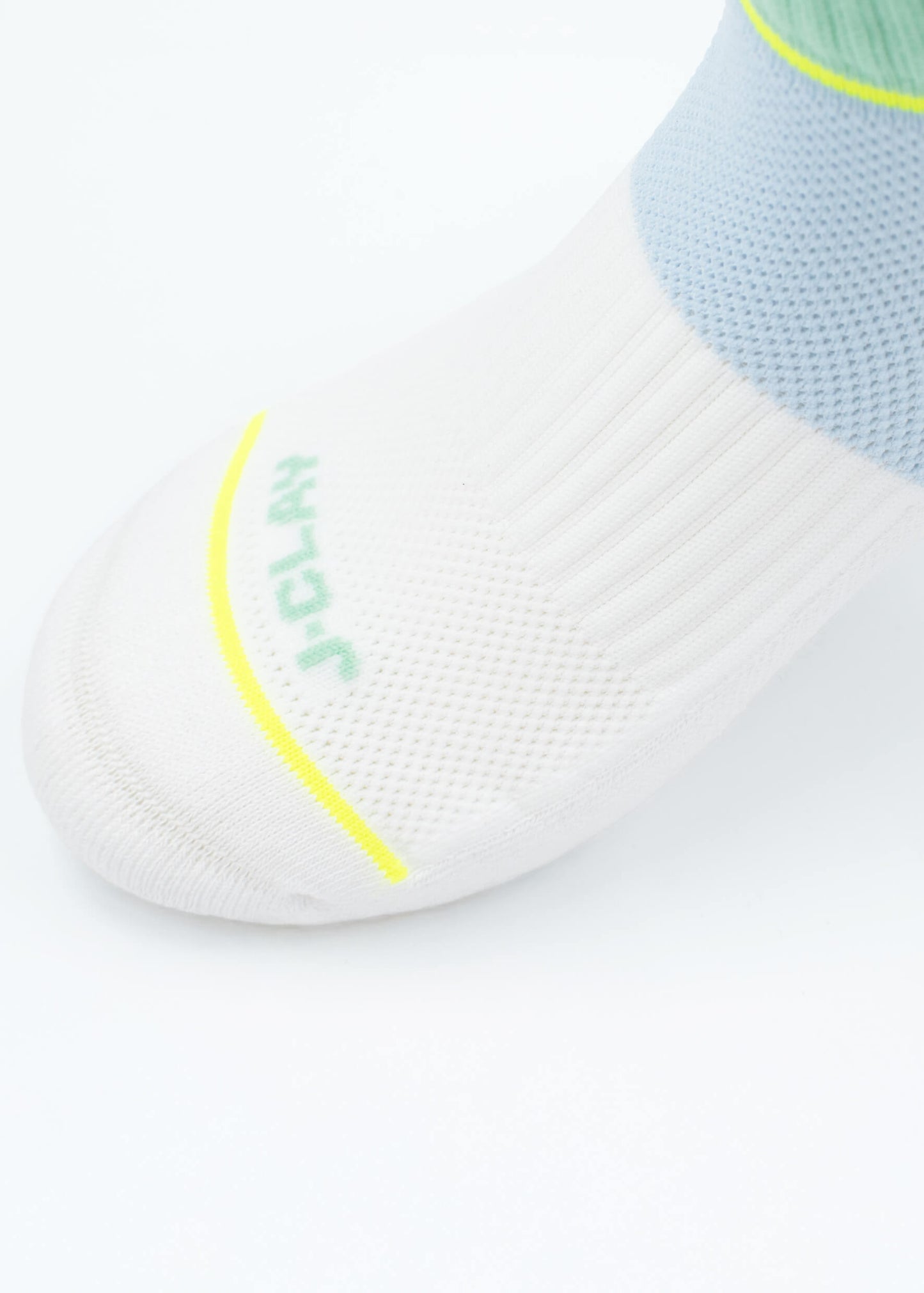 Nahaufnahme einer weißen, kurzen J.Clay-Sportsocke mit gerippter Struktur, Mesh-Details, atmungsaktivem Material, gelber Linie, grünem J.Clay-Text im Zehenbereich und gepolsterter Sohle für zusätzlichen Komfort.