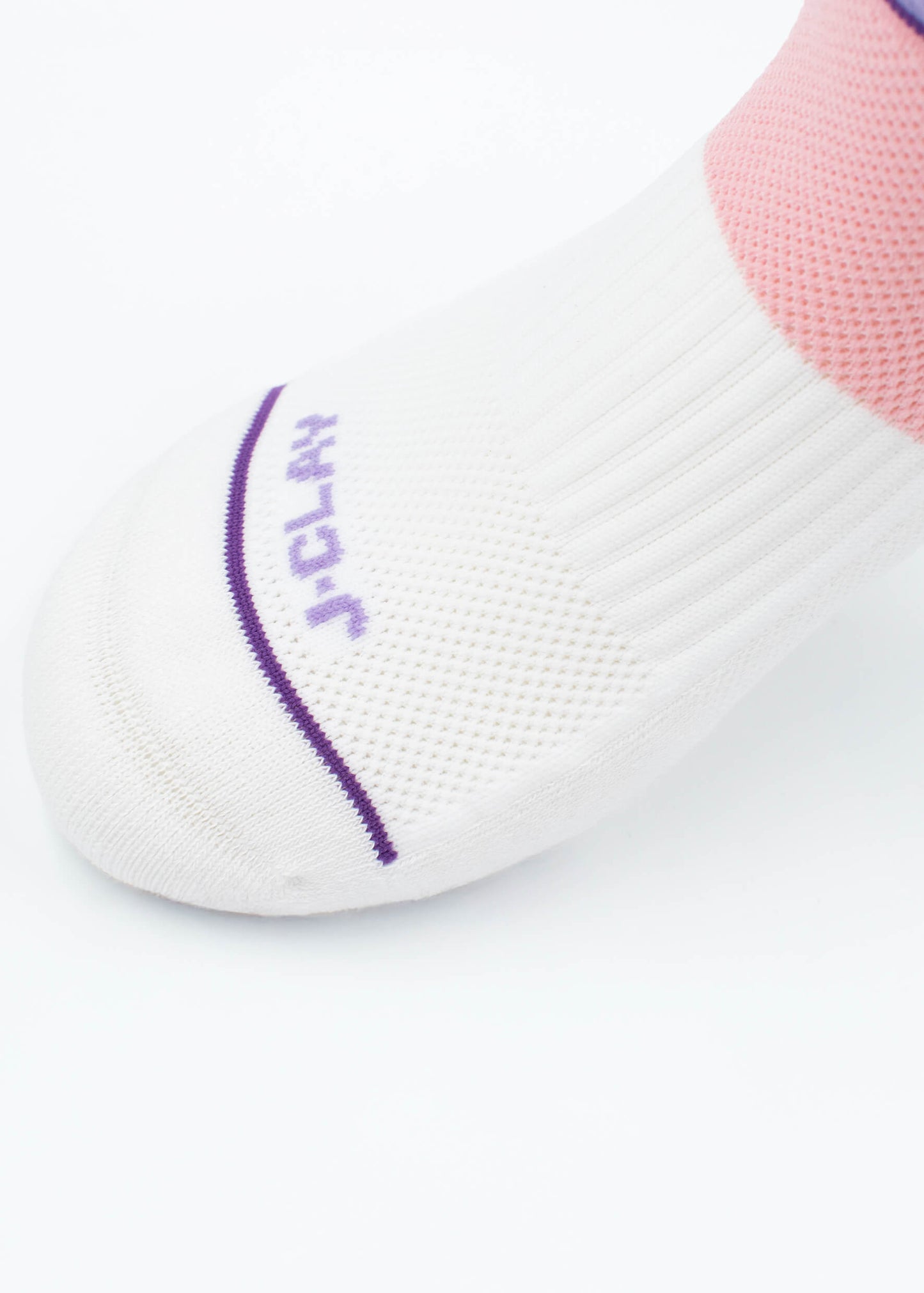 Eine Nahaufnahme eines Fußes in J.Clay Sportsocken mit lila Akzenten, "JCLAY"-Schriftzug in der Nähe der Zehen, einem rosafarbenen Bereich um den Knöchel und einer gepolsterten Sohle für zusätzlichen Komfort.