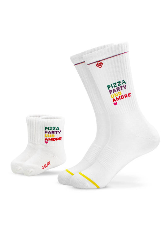 Zwei Paar weiße J.Clay-Socken - ein Erwachsener mit gelben Streifen, ein Kind mit "PLAY" in Rot auf der Sohle - beide mit buntem "PIZZA PARTY UNO & MORE"-Text. Perfekte Mini Me Socken für passende Styles.