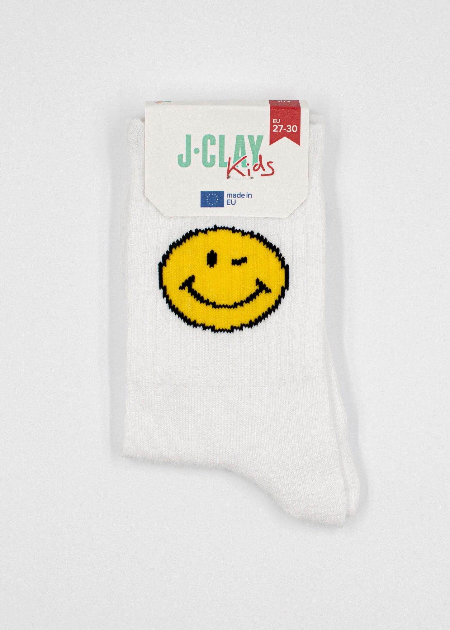 Ein Paar weiße J.Clay Kinder Tennissocken mit einem gelben Smiley-Gesicht, EU-gefertigt in Größe 27-30. Verpackt mit einem J.Clay Kids Label - ideale Socken für Kinder ab 5 Jahren.