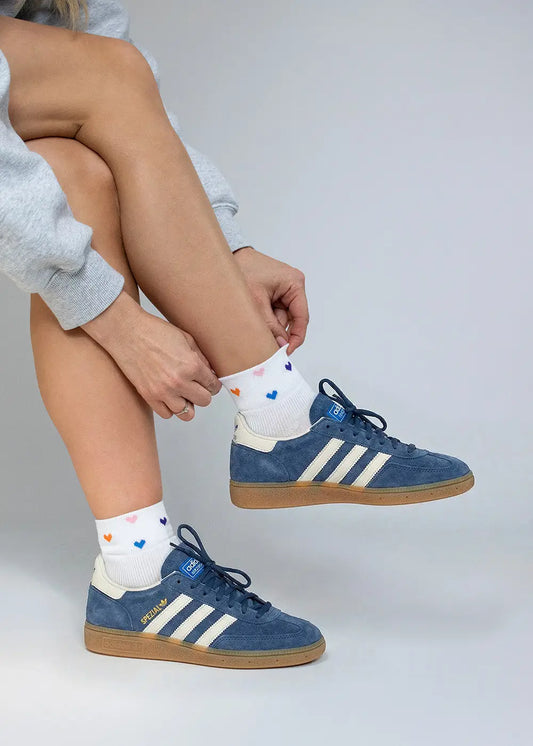 Person trägt blaue Adidas Sneaker-Socken und bunte J.Clay Spring Hearts Sneaker Socken High.