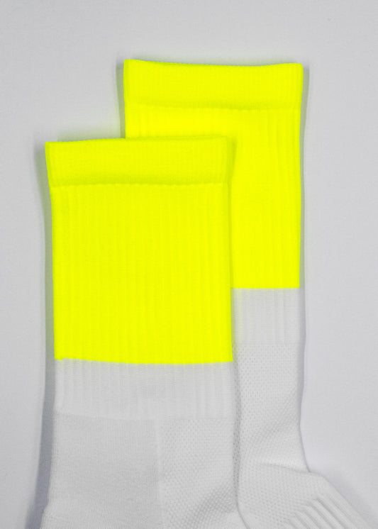 Zwei weiße J.Clay Sportsocken mit leuchtend gelben Spitzen stehen nebeneinander auf einem unifarbenen, hellen Hintergrund, der mit atmungsaktiver Maschenlüftung für Komfort sorgt.