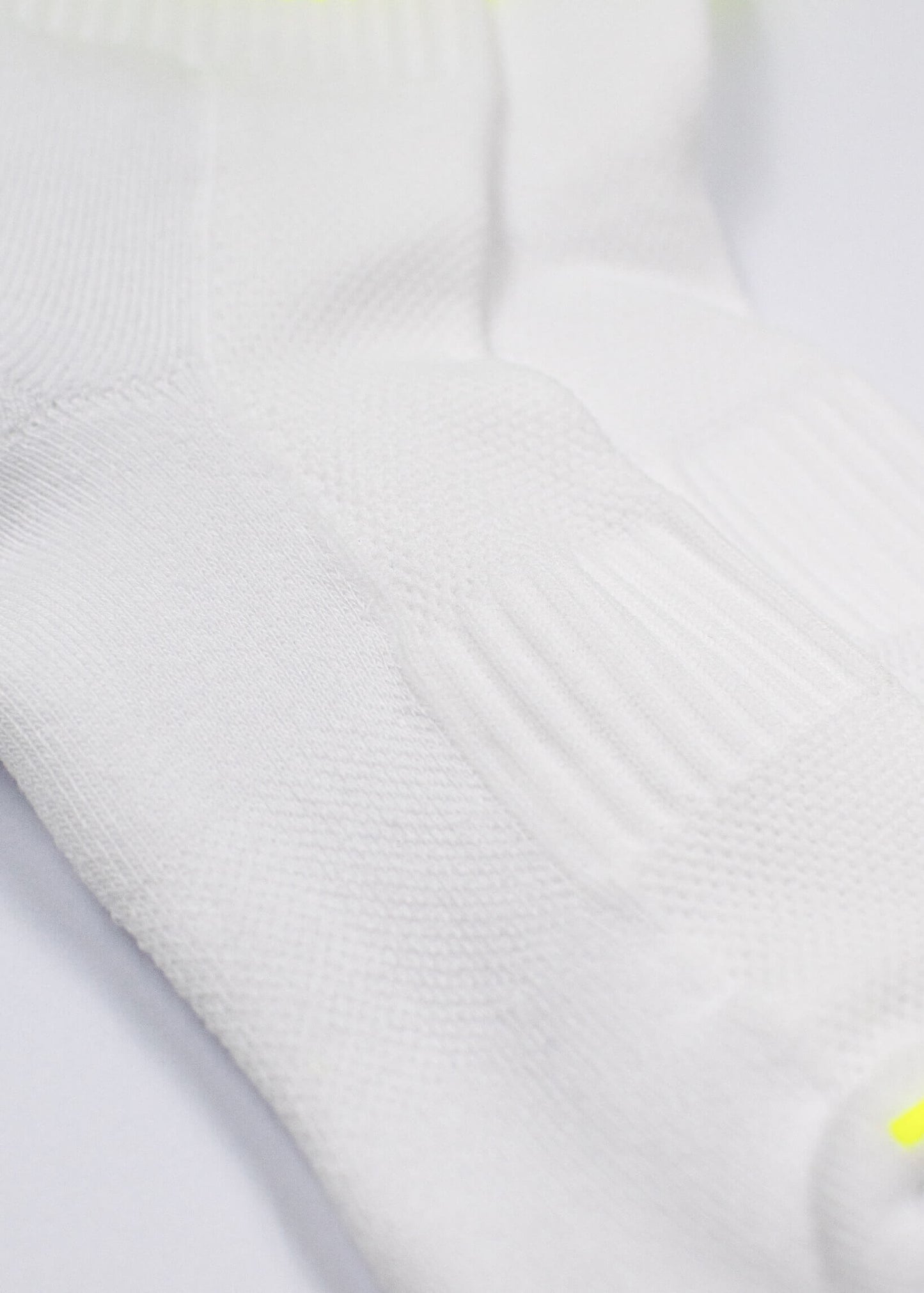 Ein Paar weiße J.Clay Sportsocken mit gelben Streifen und "Padel addicted" in Blau - ideal für Padel-Tennis-Fans. Der Hintergrund ist weiß mit einem blauen X SPORTS Logo in der oberen rechten Ecke.