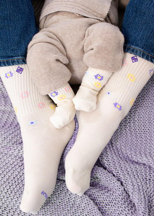 Zwei Paar cremefarbene J.Clay Mama Kind Socken - eine für Erwachsene, eine für Kinder - verziert mit pastellfarbenen Blumen in Gelb, Rosa, Blau und Lila. Perfekt für einen süßen Partnerlook!. - Mama Kind Packs