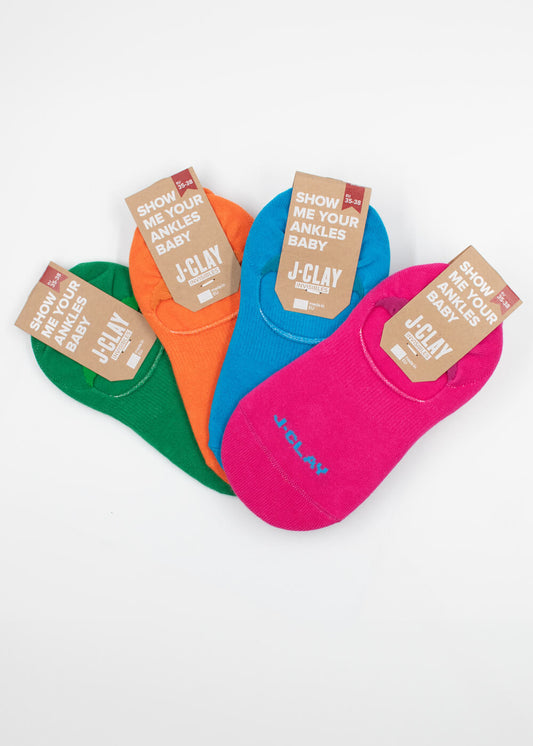 Vier Paar J.Clay unsichtbare Füßlinge in Grün, Orange, Blau und Pink sind nebeneinander angeordnet, jedes mit einem Pappanhänger, auf dem steht "Zeig mir deine Knöchel, Baby! J-Clay.