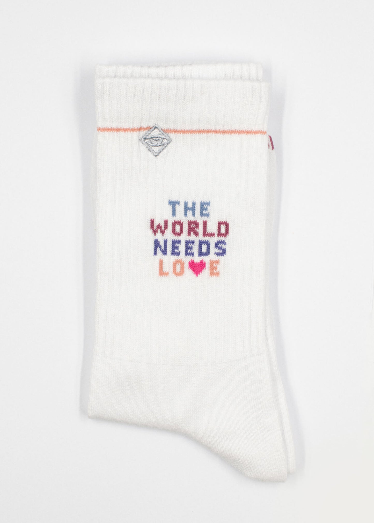 Ein Paar weiße gerippte J.Clay Tennissocken mit "THE WORLD NEEDS LOVE" in bunten Buchstaben und einem rosa Herz, ordentlich gefaltet vor einem weißen Hintergrund.
