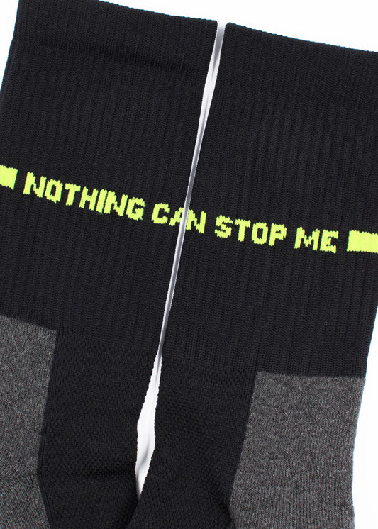Ein Paar schwarze und graue J.Clay Sportsocken nebeneinander, mit dem Schriftzug "NOTHING CAN STOP ME" in leuchtendem Gelb-Grün auf den Oberseiten, aus atmungsaktivem Material mit gepolsterter Sohle für optimalen Tragekomfort.