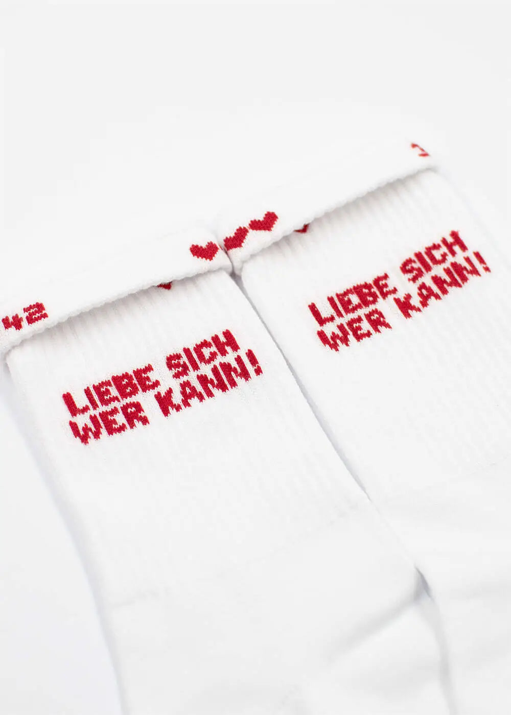 Weiße Tennissocken von J.Clay mit rotem "Liebe sich wer kann" und kleinen roten Herzen darüber.