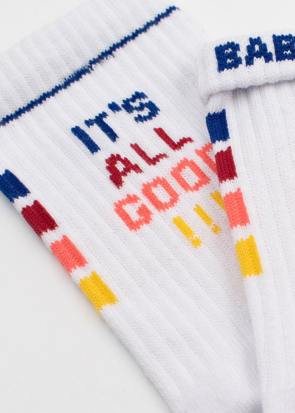 J.Clay weiße gerippte Tennissocken mit bunten Streifen und dem Aufdruck "ITS ALL GOOD!!!" in blau, rot, orange und gelb. Das obere Band einer Socke zeigt teilweise "BAB" in blau.
