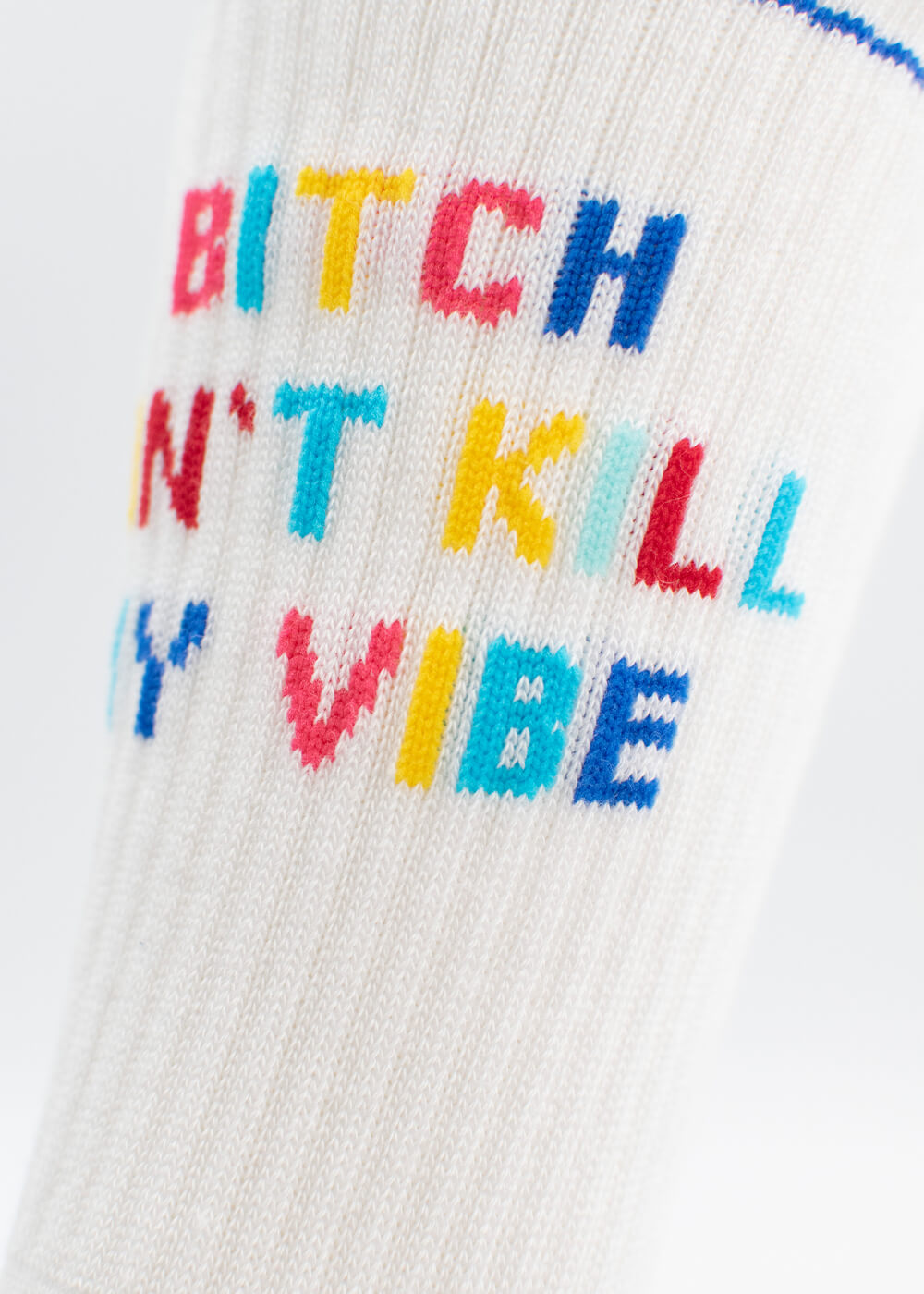 Eine Nahaufnahme der weißen gerippten J.Clay Tennissocken mit dem bunten gestickten Text "Bitch Dont Kill My Vibe" in roten, rosa, gelben, blauen und blaugrünen Buchstaben.