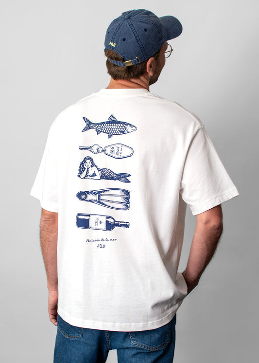 Ein Mann in einem „Ocean Kiss“-T-Shirt von J.Clay und einer blauen Mütze, von hinten gesehen, im maritimen Grafikstil.