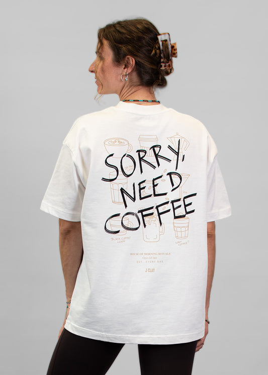 Frau mit dem Rücken zur Kamera auf einem „J.Clay Sorry Need Coffee“-T-Shirt, Off-White, Unisex, lockere Passform.