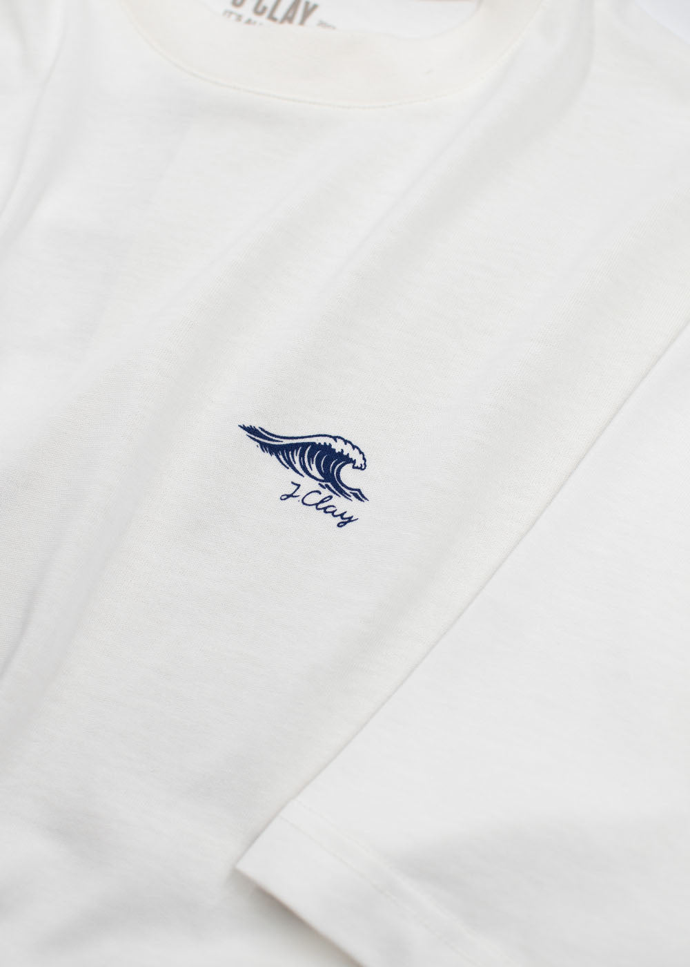 J.Clay „Ocean Kiss“-T-Shirt, weiß mit kleiner blauer Welle und Logo auf der Brust.
