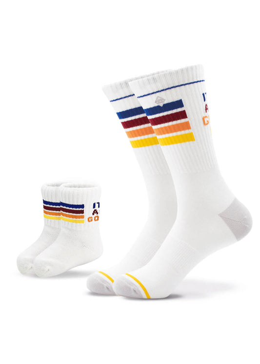 Zwei Paar J.Clay Partner-Look Socken - eines für Erwachsene, eines für Kinder - in Weiß mit horizontalen blauen, roten, orangen und gelben Streifen sowie kleinem Text und Grafik am oberen Rand.