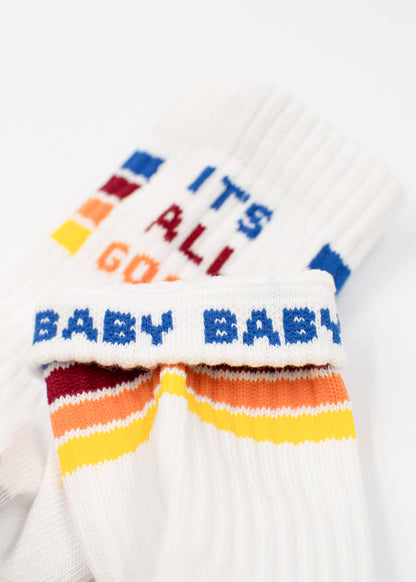 Eine Nahaufnahme von J.Clay Kinder Tennissocken: weiße Socken mit bunten Streifen. Auf der einen steht ITS ALL GOOD in blau, rot und orange, auf der anderen BABY BABY in blau am Bündchen. Ideale Kindersocken ab 5 Jahren.