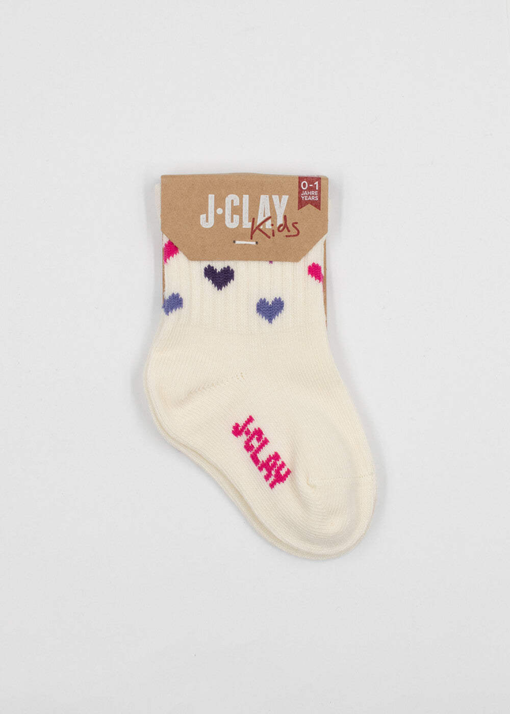Ein Paar cremefarbene Baby Socken von J.Clay mit blauen, lila und rosa Herzmustern und "J-CLAY" in rosa. Ausgestellt mit einem braunen Etikett mit der Aufschrift "Kinder Socken 0-4 Jahre.