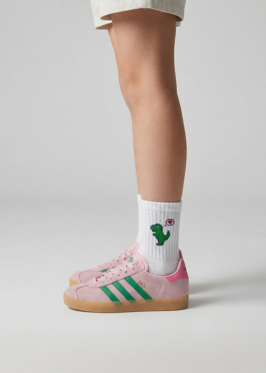 Kind in rosa und grünen Turnschuhen trägt J.Clay Dino Love - Kindersocken mit Cartoon-Dinosaurier-Design.