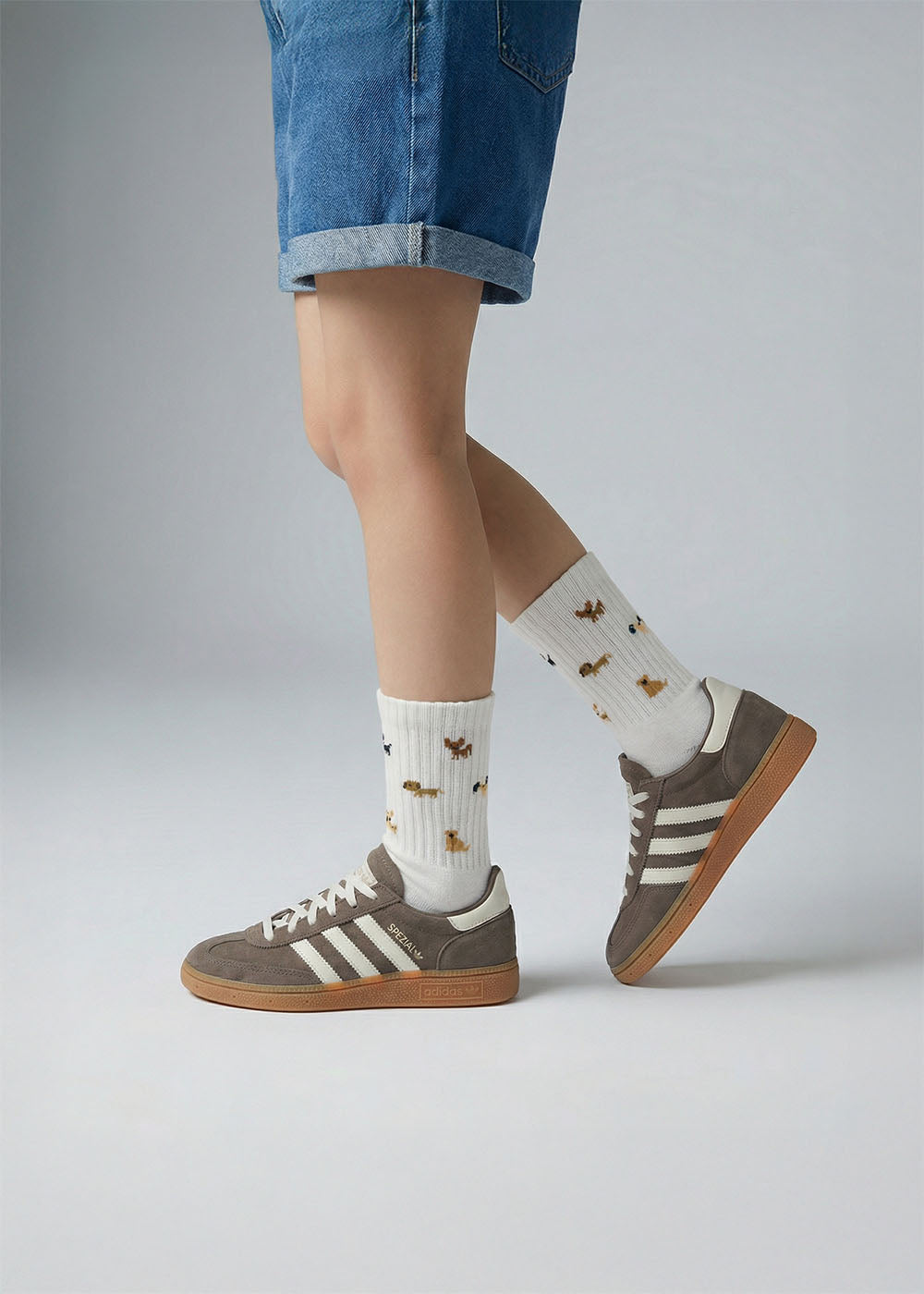 Person in Jeansshorts, braunen Adidas-Turnschuhen und J.Clay Doggie - Kids im Schneidersitz.