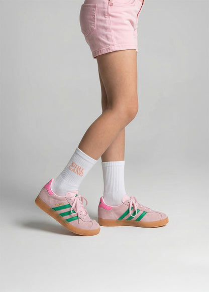 Person in rosa Shorts, J.Clay Girl Gang - Kids Socken und rosa Adidas Turnschuhen mit grünen Streifen.