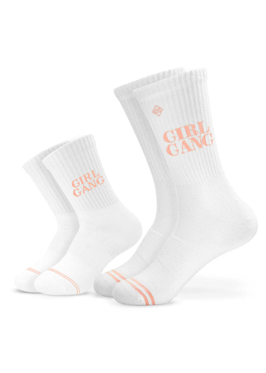 Zwei Paar weiße J.Clay Partner-Look-Socken - ein kleines und ein großes Paar - mit hellrosa Zehenstreifen und dem Schriftzug "GIRL GANG" in Rosa auf dem Bündchen, perfekt für einen passenden Look.