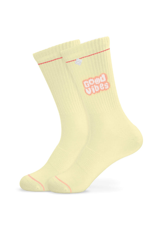 Ein Paar hellgelbe J.Clay-Crew-Socken mit einem roten Streifen am oberen Ende und "Good Vibes" in Rosa und Weiß an der Seite, dargestellt auf einem unsichtbaren Fuß vor einem schlichten weißen Hintergrund.