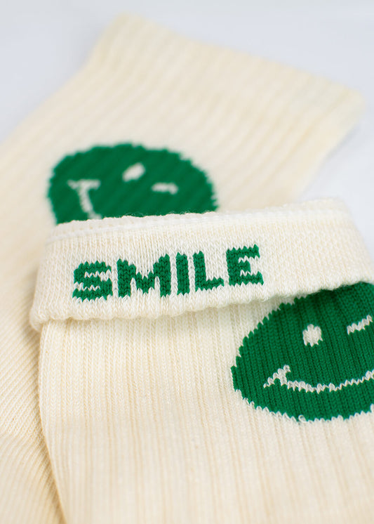 Zwei Paar cremefarbene J.Clay-Crew-Socken, die jeweils ein grünes, lächelndes Gesicht an der Seite aufweisen. Die Green Smile Socken sind in Erwachsenen- und Kindersockengrößen erhältlich - ideal für Eltern-Kind-Socken und passende Familienoutfits. - Mama Kind Packs