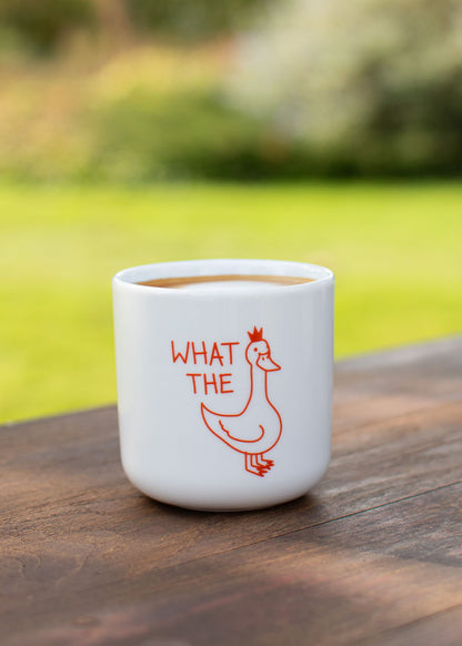 J.Clay „What the Duck“ – Tasse mit Entenmotiv auf einem Holztisch im Freien.