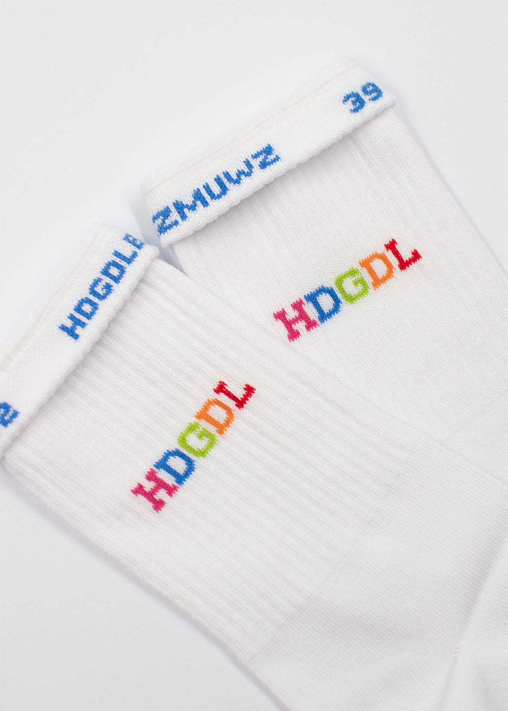 Zwei weiße J.Clay HDGDL-Socken mit regenbogenfarbenem HDGDL und blauem Bündchentext.