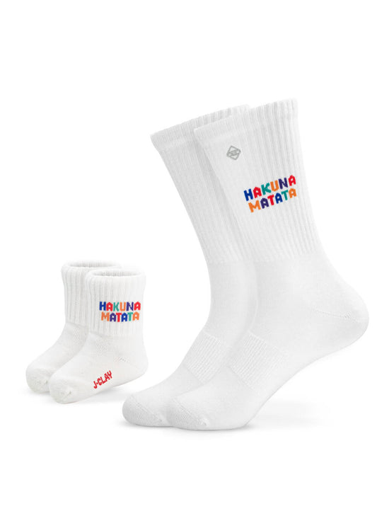 Zwei Paar weiße, gerippte Socken von J.Clay - in Erwachsenen- und Babygröße - sind der perfekte Partnerlook. Beide tragen den Schriftzug "HAKUNA MATATA" in bunten Buchstaben, die Babysocken zusätzlich den roten Schriftzug "JCLAY" an der Seite.