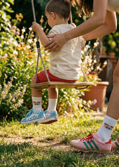 Auf dem Bild „J.Clay Hakuna Matata Fam Pack“ schubst ein Erwachsener ein Kind auf einer Holzschaukel in der Sonne.
