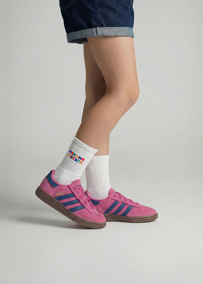 Person in rosa Turnschuhen, Jeansshorts und J.Clay Hakuna Matata - Kids Socken in Weiß.