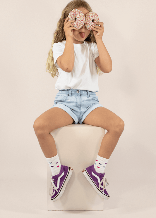 Drei Paar cremefarbene Kindersocken von J.Clay (ab 5 Jahren) mit gerippten Oberteilen, auf denen kleine lila, rosa und rote Herzen gleichmäßig über den Stoff verstreut sind. - Kinder Socken ab 5 Jahren