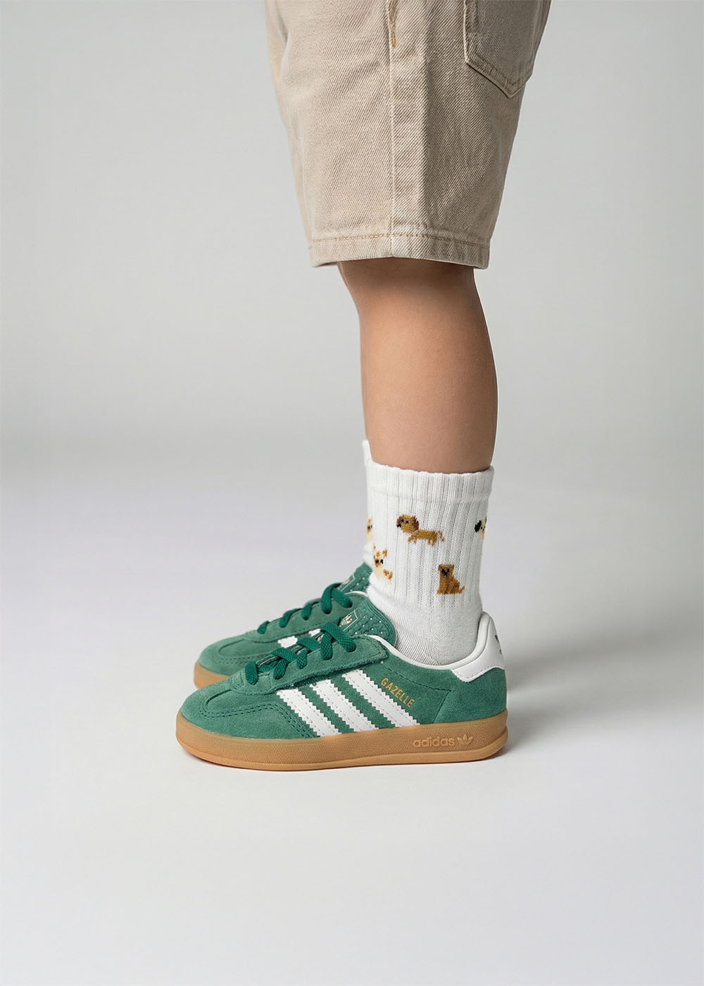 Kind in grünen Adidas-Turnschuhen, beigen Shorts und J.Clay Doggie - Mini-Socken.